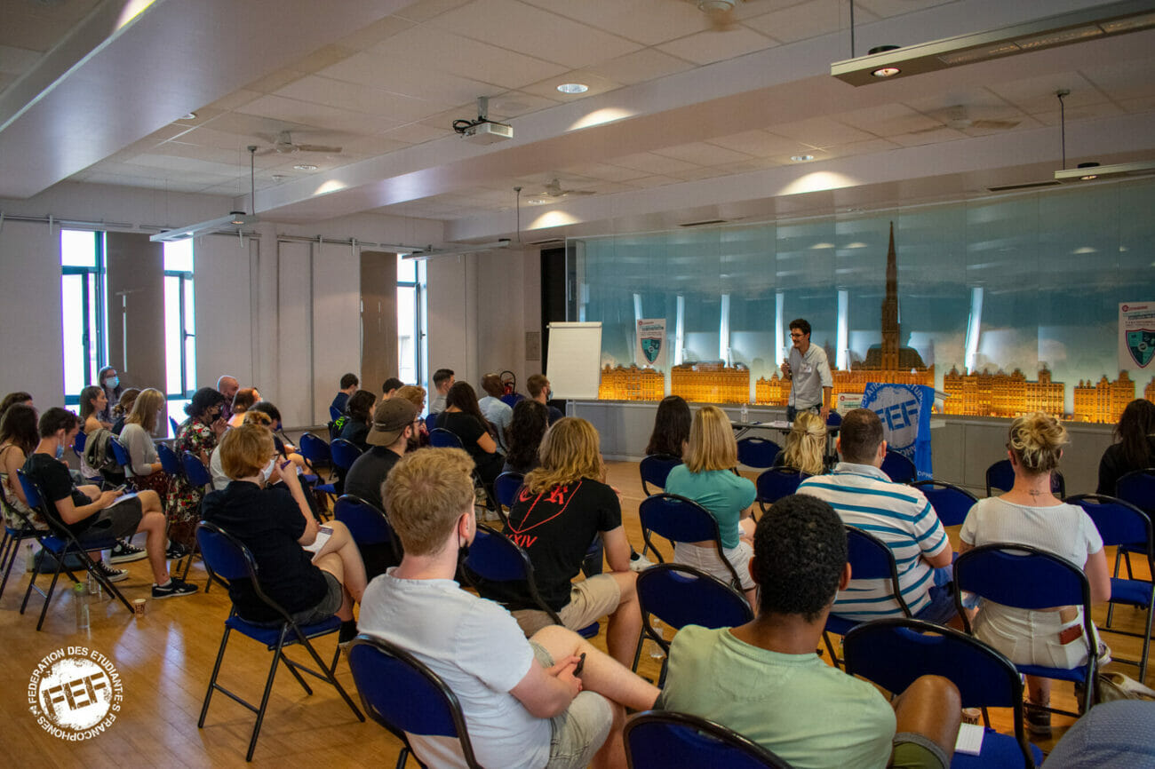Groupe d'étudiants assis sur des chaises qui écoute quelqu'un debout présenter une formation